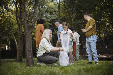 Sozial integrative Gruppe von Freiwilligen sammelt Plastikmüll in einem öffentlichen Park - HAPF03702