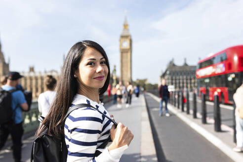Smiling woman with backpack enjoying vacations in London city - WPEF07958