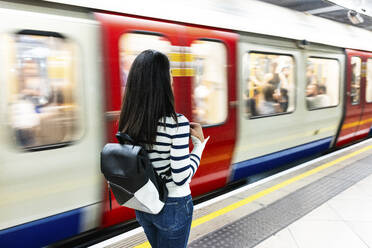 Frau mit Rucksack steht in der Nähe der U-Bahn am Bahnhof - WPEF07964