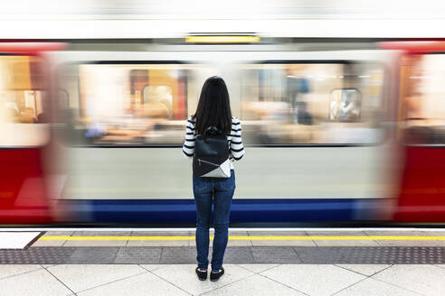 Frau mit Rucksack steht vor der U-Bahn am Bahnhof - WPEF07965