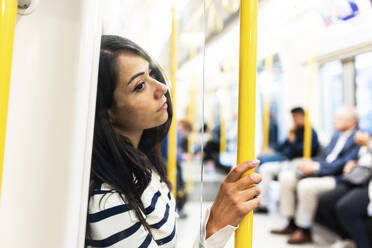 Nachdenkliche Frau, die einen Stock hält und in der U-Bahn reist - WPEF07975