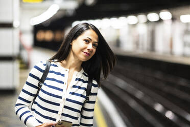 Smiling woman waiting for subway at station - WPEF07977