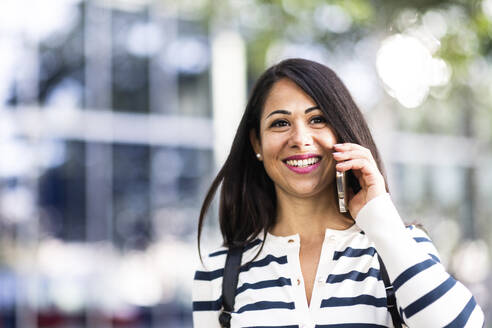 Glückliche Frau, die mit einem Mobiltelefon spricht - WPEF07991