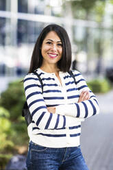 Happy woman standing with arms crossed - WPEF07993