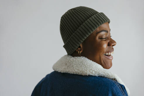 Happy woman wearing knit hat against white background - EBSF04163
