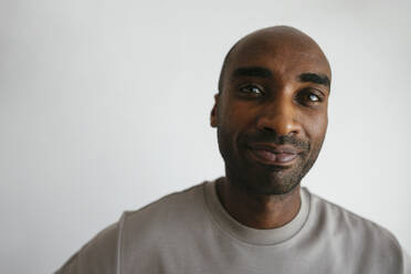 Lächelnder Mann mit rasiertem Kopf vor weißem Hintergrund - EBSF04171