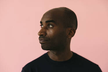 Mann mit rasiertem Kopf vor rosa Hintergrund - EBSF04172