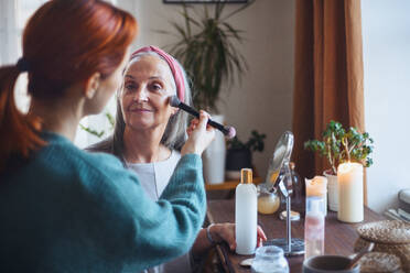 Caregiver helping her senior client with a make up. - HPIF32538
