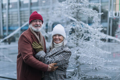 Portrait of seniors in winter at outdoor ice skating rink. Smiling, embracing each other. - HPIF32543