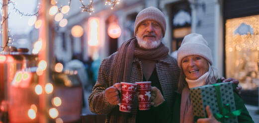 Happy senior couple enjoying outdoor christmas market, buying gifts. Christmas banner with copy space. - HPIF32559