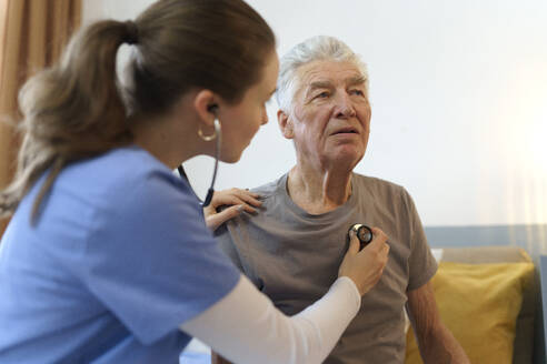 Young nurse taking care of elderly senior in his home. - HPIF32596