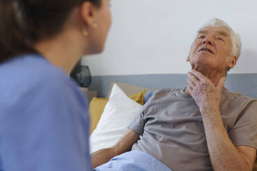 Young nurse taking care of elderly senior in his home. - HPIF32598