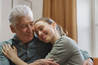 Young woman hugging her grandfather in the home. - HPIF32609