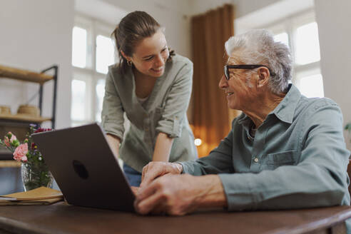 Granddaughter showing something to her grandfather on a laptop. - HPIF32611