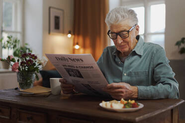 Senior man reading newspaper in the apartment. - HPIF32613