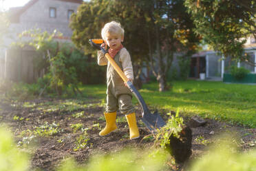 Little boy with a spade working in garden during autumn day. - HPIF32617