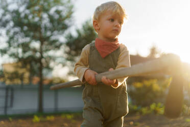 Little boy with a hoe working in garden during autumn day. - HPIF32650
