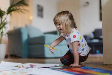Niedliches kleines Mädchen, das mit Buntstiften zeichnet und auf dem Boden im Wohnzimmer sitzt. - HPIF32701