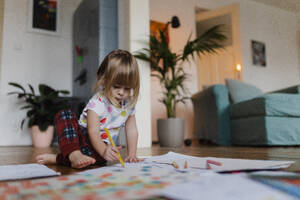 Cute little girl drawing with crayons, sitting on the floor in the living room. - HPIF32702