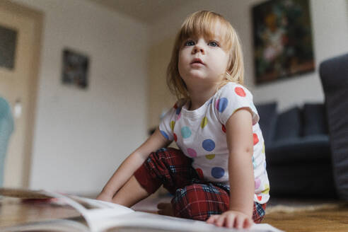 Cute little girl with bangs reading book sitting on the floor in her child's room. - HPIF32709