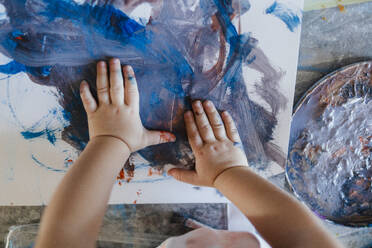 Cute little girl painting with her own hands, using tempera paint. Finger painting creative activity. - HPIF32713