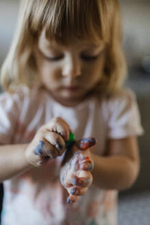 Porträt eines kleinen Mädchens mit unordentlichen, mit Farbe befleckten Händen. Künstlerisches Kind, das unordentlich wird und Spaß hat. - HPIF32717