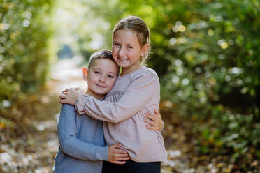 Portrait of little children, siblings, hugging in a forest. - HPIF32734