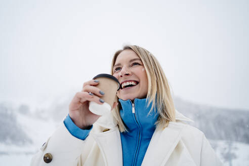 Lächelnde Frau hält Kaffeetasse unter Himmel - MDOF01759