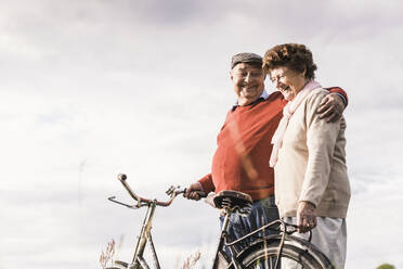 Happy senior couple spending leisure time under cloudy sky - UUF30726