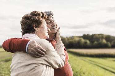 Happy senior couple spending leisure time and embracing each other at field - UUF30727