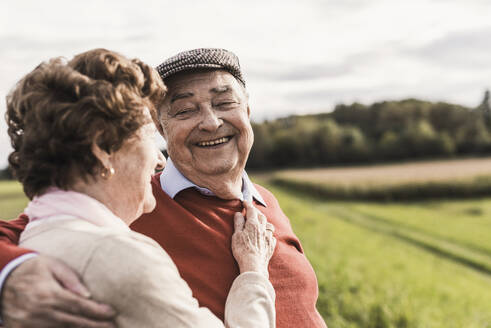 Glückliches älteres Paar verbringt seine Freizeit auf einem Feld an einem sonnigen Tag - UUF30728