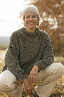 Happy woman crouching at field - EBSF04182