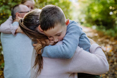 Little boy embracing his mother during family walk in a forest. - HPIF32771