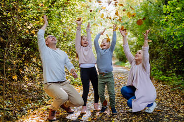 Happy family having fun with foliage in autumn forest. - HPIF32776