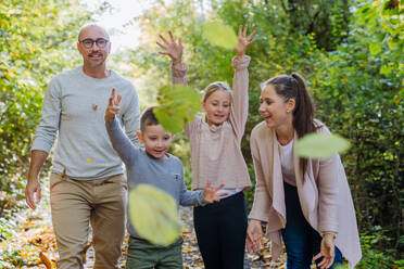 Happy family having fun with foliage in autumn forest. - HPIF32778