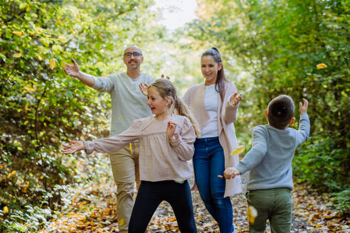 Happy family having fun with foliage in autumn forest. - HPIF32779