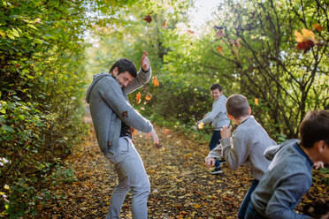 Father with his children having fun in forest, throwing foliage. - HPIF32792