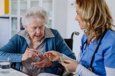 Nurse giving pills to senior woman in her home. - HPIF32795