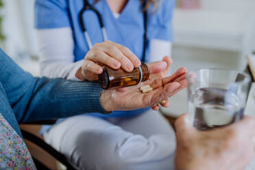 Close up of nurse giving pills to senior woman in her home. - HPIF32797