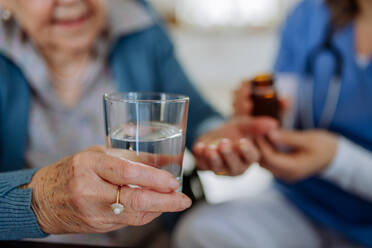 Close-up of nurse giving pills to senior woman in her home. - HPIF32798