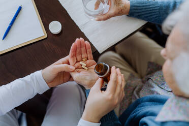 Top view of nurse giving pills to senior woman in her home. - HPIF32812