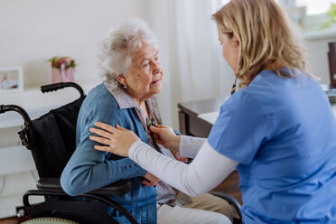 Krankenschwester untersucht älteren Patienten mit Stethoskop zu Hause. - HPIF32815