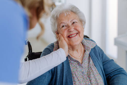 Nahaufnahme einer Krankenschwester, die die Wange einer älteren Frau streichelt. - HPIF32827