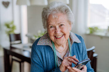Porträt einer lächelnden älteren Frau mit Smartphone. - HPIF32842