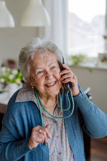 Porträt einer älteren Frau, die mit einem Smartphone telefoniert. - HPIF32844