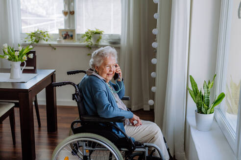 Porträt einer älteren Frau im Rollstuhl, die anruft. - HPIF32847