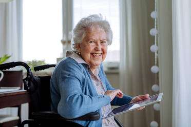 Senior woman on a wheelchair scrolling digital tablet. - HPIF32850