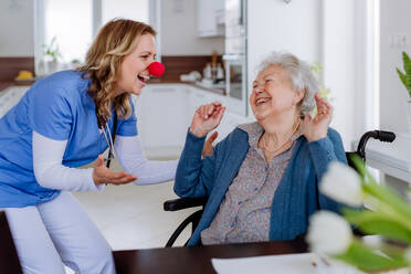 Krankenschwester mit Clownsnase, die sich mit einer älteren Kundin amüsiert. - HPIF32872
