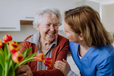 Senior woman and nurse with a tulip bouquet. - HPIF32882