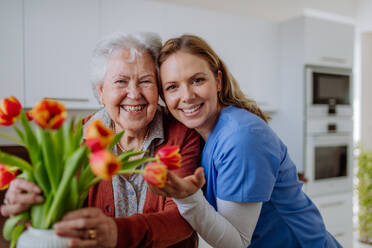 Senior woman and nurse with a tulip bouquet. - HPIF32884